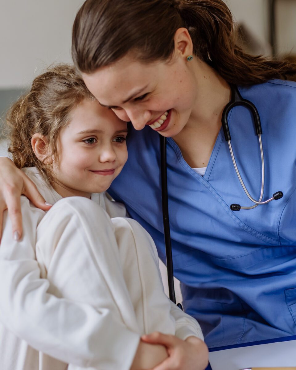 Young doctor consoling little girl in a hospital room.